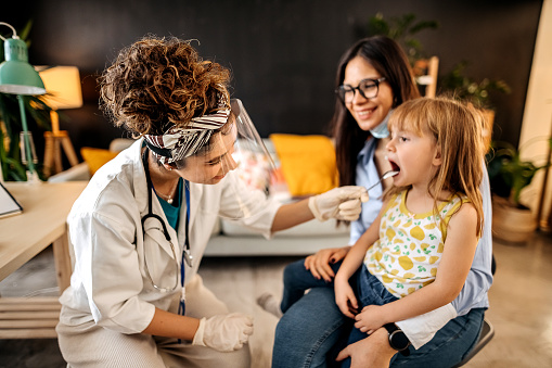 Doctor examining a young girl's throat.