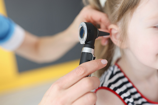 Doctor examining a young girl's ear.